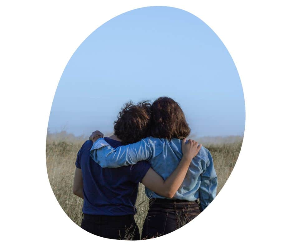 Kaksi henkilöä halaavat katsellen horisonttiin