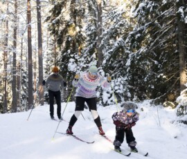 Perheeseemme kuuluvat minä, 5-vuotias lapseni ja puolisoni “Suksenvoitelija”. Kun tapasin Suksenvoitelijan, olin juuri eronnut pitkästä parisuhteesta ja päättänyt aloittaa tien kohti itsellistä äitiyttä. Alusta asti oli selvää, että seikkailumme kulkisi omia polkujaan välillä risteillen ja välillä kulkien omaa suuntaansa, koska määränpäämme olivat erilaiset. Asun lapseni kanssa kahdestaan. Eri kaupungissa asuva Suksenvoitelija on ollut erottamaton osa lapseni elämää aina. Joudumme hyvin usein vastaamaan kysymykseen, miksi emme asu yhdessä, vaikka olemme perhe. Muilla on suuri tarve määritellä meidät. Meille perhemuotomme nimeäminen ei ole oleellista. Vaikka yhteiskunnan silmissä emme ole virallisesti perhe, meille tärkeintä on seikkailla samassa retkikunnassa ja nauttia elämästä ja hyvistä eväistä. Kuvassa Emilia (keskellä) sekä hänen puolisonsa ja lapsensa. Kuvaaja Eeva-Maria Brotherus.