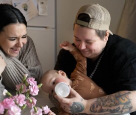 Perheeseemme kuuluvat transmies ja cis-nainen -vanhemmat ja poikavauva. Hakeuduimme lahjasoluhoitoihin talvella 2022. Koko maailma pysähtyi, kun lääkäri totesi vappuna 2024, että sykettä ei löytynyt. Olimme juuri edellisellä viikolla nähneet ultrassa sydämen sykkeen. Loppukesällä 2024 tehdystä inseminaatiosta alkoi raskaus, josta saimme poikamme syliimme. Olemme ikuisesti kiitollisia. Hoidot ja keskenmeno olivat todella rankka kokemus, ja toive pikkusisaruksesta on toistaiseksi vielä iso ehkä. Toivomme, että sateenkaariperhettämme kohdellaan samalla tavalla kuin mitä tahansa perhettä. Toivomme suvaitsevaisuutta ja hyväksyntää jokaiselta jokaista kohtaan. Perheessämme on parasta hyvä meininki ja iso rakkaus, jota saamme myös ystäviltä ja sukulaisilta. Biologia ei ole suora määritelmä perheelle eikä vanhemmuudelle. Kuvassa Veera (vas.), hänen puolisonsa sekä perheen vauva. Kuvaaja Eeva-Maria Brotherus.